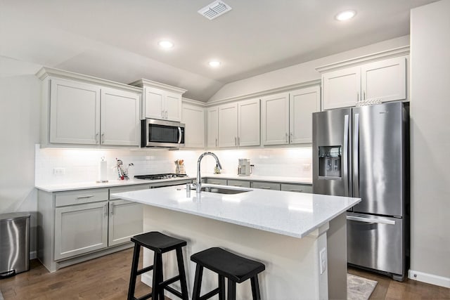 kitchen with sink, a center island with sink, lofted ceiling, and appliances with stainless steel finishes