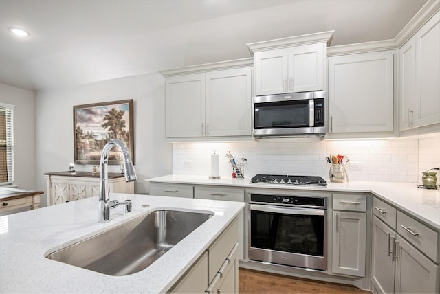 kitchen with sink, backsplash, light stone countertops, and appliances with stainless steel finishes