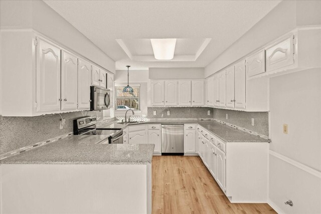 kitchen featuring pendant lighting, light wood-type flooring, white cabinetry, and appliances with stainless steel finishes