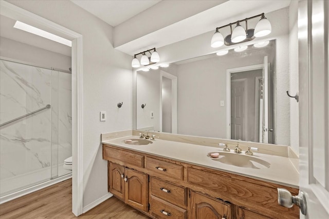 bathroom featuring hardwood / wood-style floors, vanity, toilet, and a shower with shower door