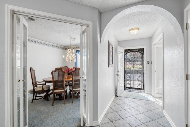 tiled foyer featuring a textured ceiling, a chandelier, and a healthy amount of sunlight