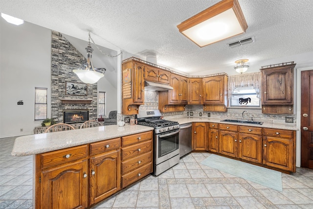 kitchen featuring a fireplace, decorative light fixtures, sink, kitchen peninsula, and stainless steel appliances