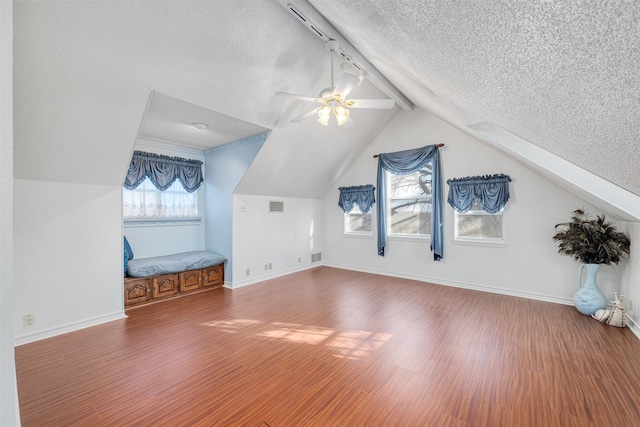 additional living space featuring hardwood / wood-style flooring, ceiling fan, lofted ceiling with beams, and a textured ceiling