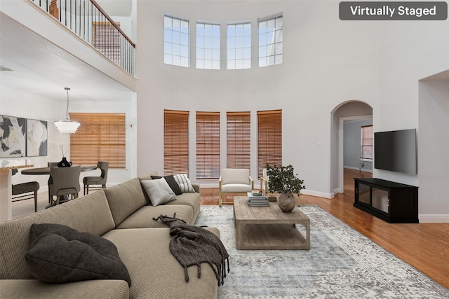 living room featuring a chandelier, a towering ceiling, and hardwood / wood-style flooring