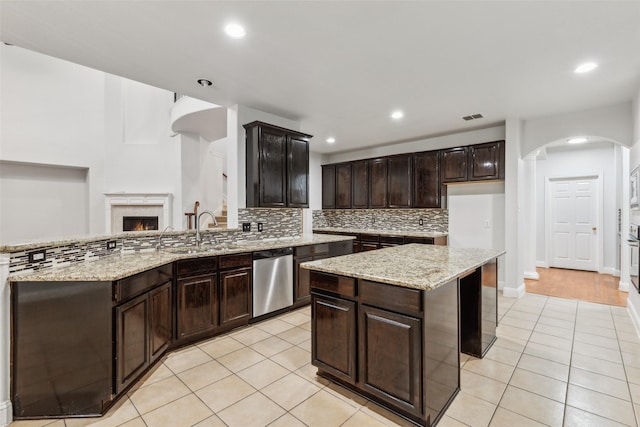 kitchen with dishwasher, light tile patterned flooring, light stone counters, and dark brown cabinets