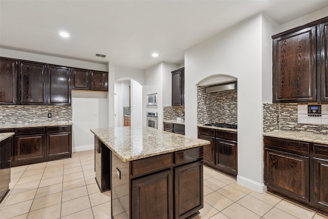 kitchen featuring light tile patterned floors, dark brown cabinets, black gas stovetop, and stainless steel oven