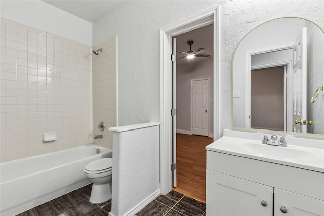 full bathroom featuring vanity, toilet, tiled shower / bath, and ceiling fan