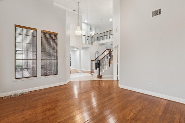 interior space featuring ornate columns, hardwood / wood-style floors, and a high ceiling