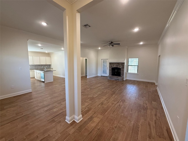 unfurnished living room with crown molding, dark hardwood / wood-style floors, a fireplace, and ceiling fan