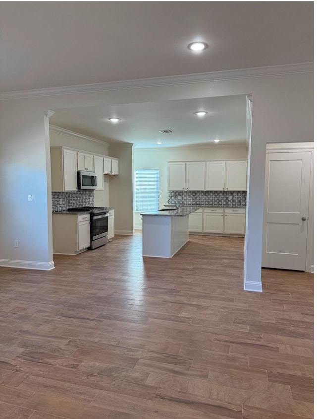 kitchen with white cabinetry, ornamental molding, stainless steel appliances, and light hardwood / wood-style floors