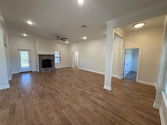 unfurnished living room with dark wood-type flooring, ceiling fan, crown molding, and a brick fireplace