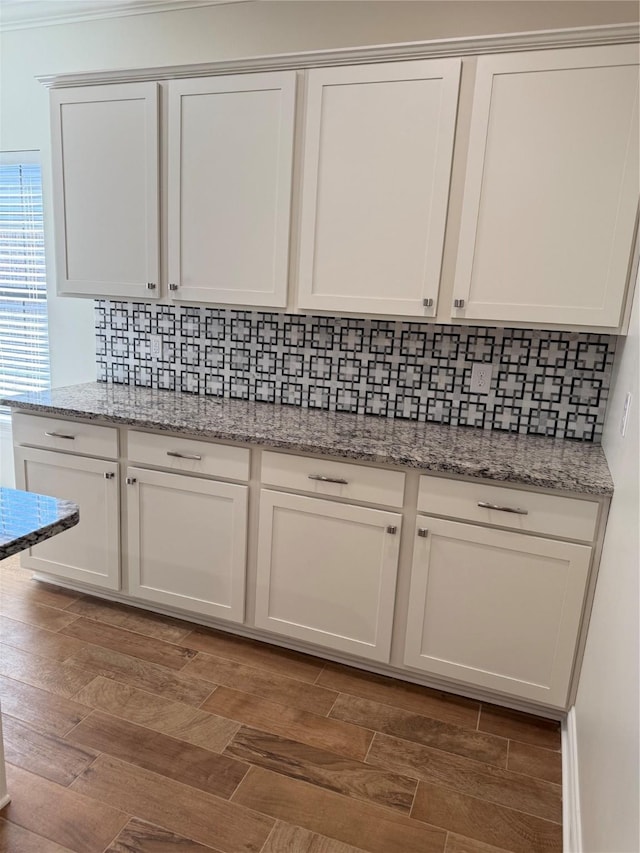 details with tasteful backsplash, dark hardwood / wood-style flooring, light stone countertops, and white cabinets