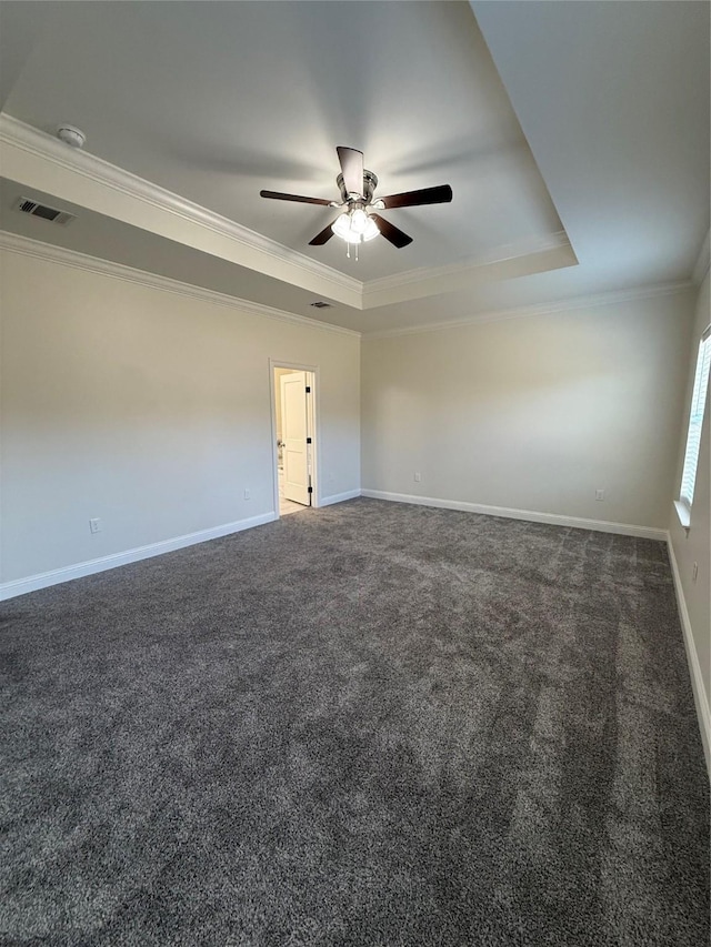 spare room with dark colored carpet, crown molding, ceiling fan, and a tray ceiling