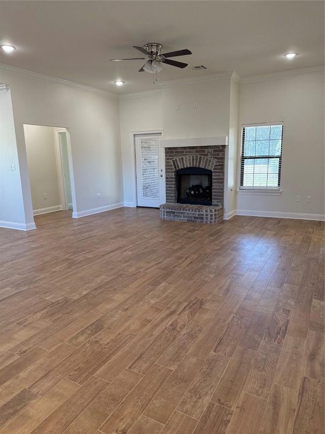 unfurnished living room with light hardwood / wood-style flooring, a brick fireplace, ceiling fan, and crown molding