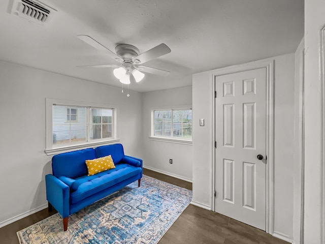 living area featuring ceiling fan and dark wood-type flooring