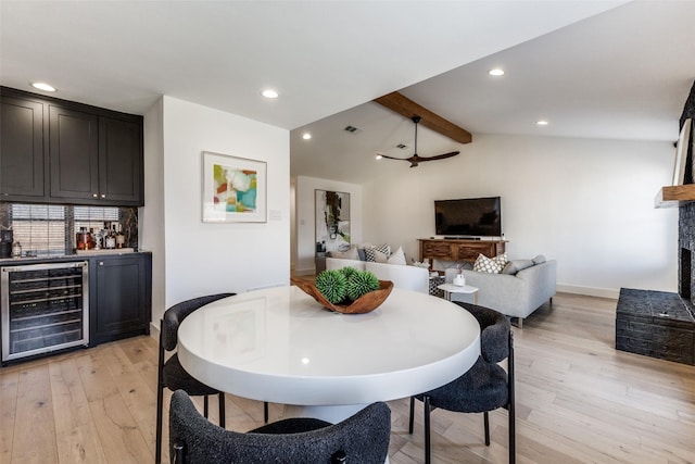 dining room with a brick fireplace, wine cooler, lofted ceiling with beams, bar area, and light hardwood / wood-style floors