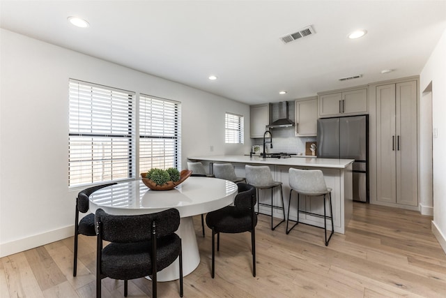 dining space with sink, a wealth of natural light, and light hardwood / wood-style flooring