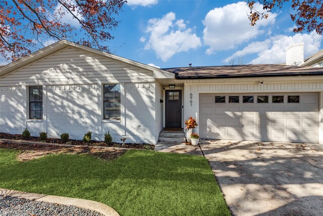 ranch-style house with a garage and a front lawn