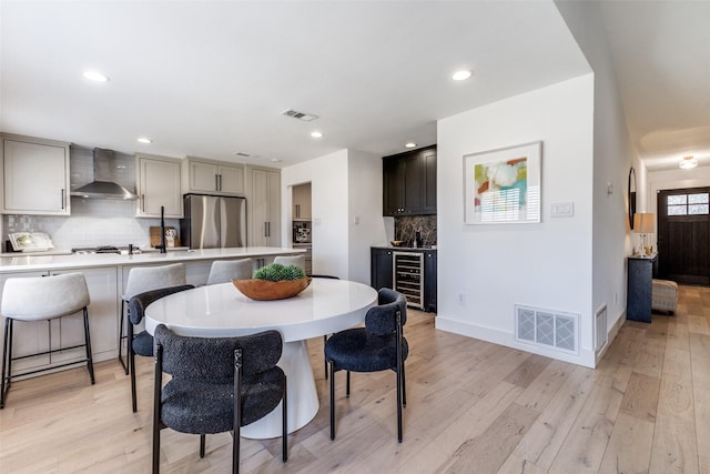 dining room with light hardwood / wood-style floors and beverage cooler