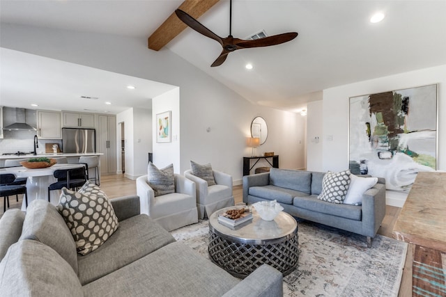 living room with lofted ceiling with beams, ceiling fan, and light wood-type flooring