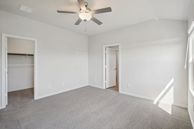 unfurnished bedroom featuring light carpet, a closet, a spacious closet, and ceiling fan