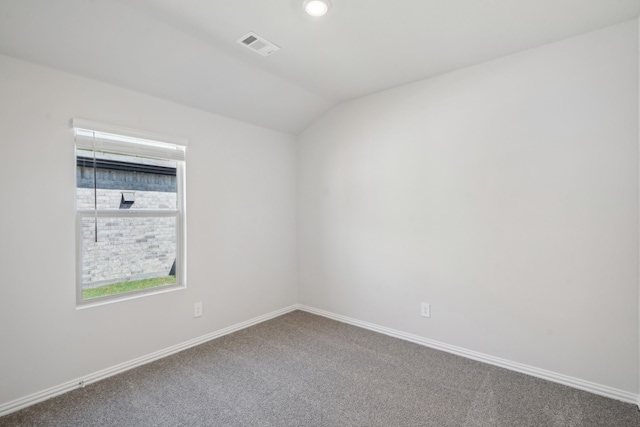 carpeted empty room with vaulted ceiling