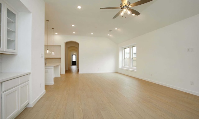 unfurnished living room featuring lofted ceiling, ceiling fan, and light wood-type flooring