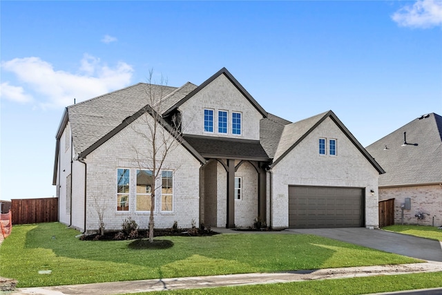 french provincial home featuring driveway, an attached garage, fence, a front lawn, and brick siding