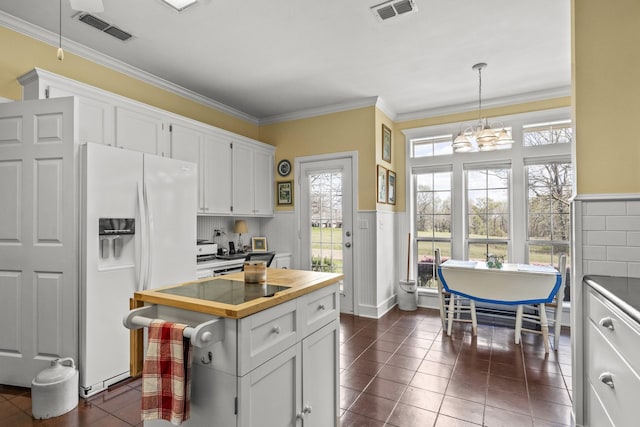 kitchen with wood counters, white cabinets, dark tile patterned floors, white fridge with ice dispenser, and decorative light fixtures