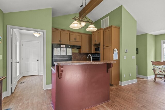 kitchen with a kitchen breakfast bar, lofted ceiling with beams, backsplash, black refrigerator, and a center island with sink