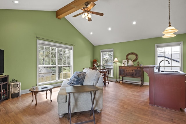 living room with lofted ceiling with beams, ceiling fan, wood-type flooring, and sink