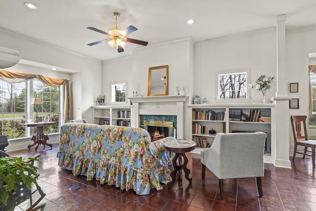 living room featuring dark tile patterned floors, ceiling fan, ornamental molding, and a premium fireplace