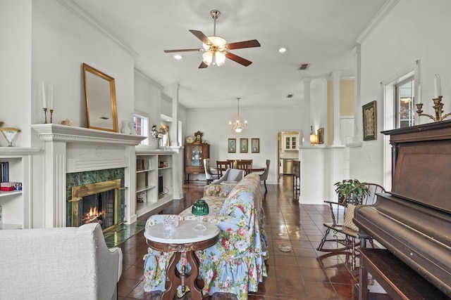 living room with dark tile patterned flooring, ceiling fan with notable chandelier, a premium fireplace, and crown molding