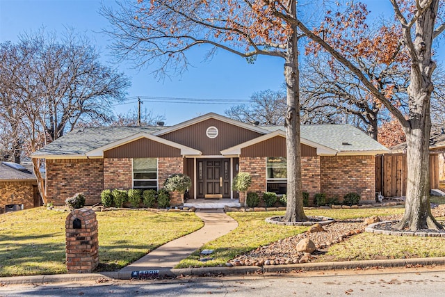 view of front facade featuring roof with shingles, fence, a front lawn, and brick siding