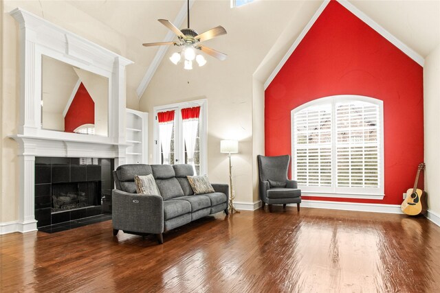 sitting room featuring hardwood / wood-style floors, high vaulted ceiling, built in shelves, ceiling fan, and a tiled fireplace