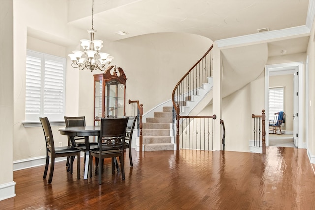 dining room featuring hardwood / wood-style floors, a healthy amount of sunlight, and an inviting chandelier