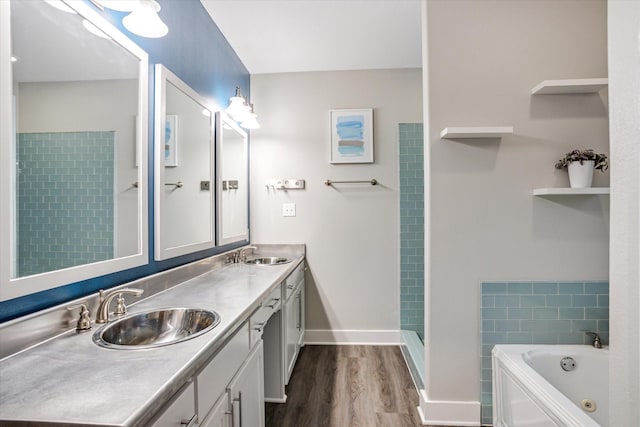 bathroom with double vanity, a sink, a tub with jets, and wood finished floors