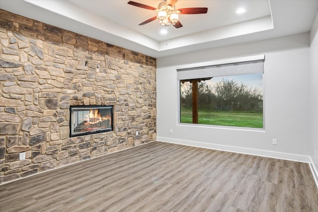 unfurnished living room featuring wood finished floors, a fireplace, and a raised ceiling