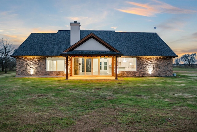 back of property featuring french doors, a lawn, a chimney, and a shingled roof