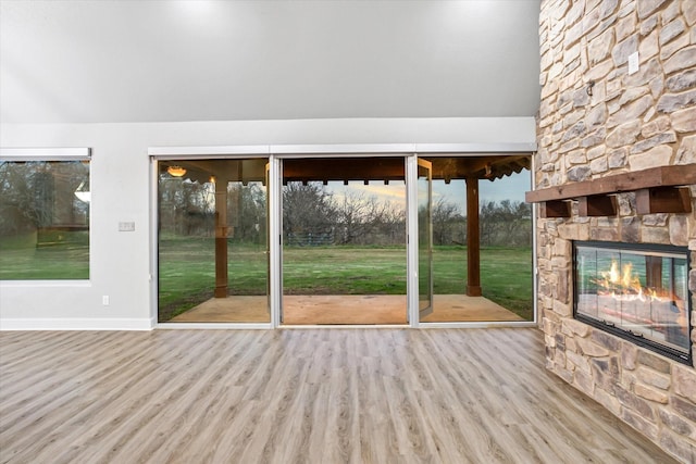 doorway to outside featuring baseboards, an outdoor stone fireplace, and wood finished floors