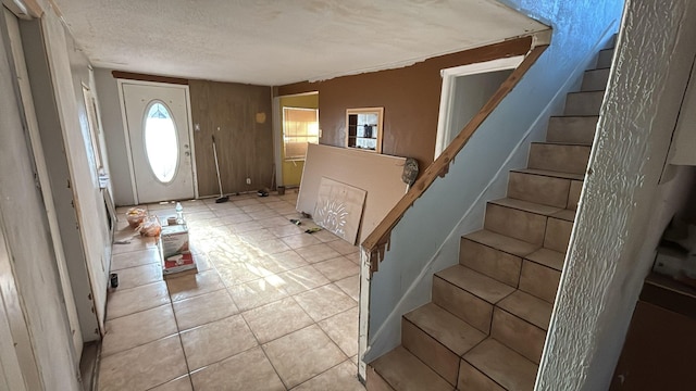 foyer entrance with light tile patterned flooring and a textured ceiling