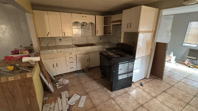 kitchen with black range with electric stovetop, light tile patterned floors, and sink