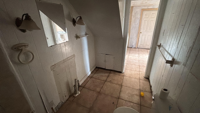 hall featuring tile patterned flooring and wood walls