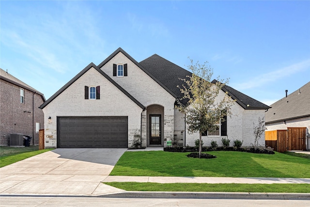 french country style house featuring central AC unit, a garage, and a front lawn