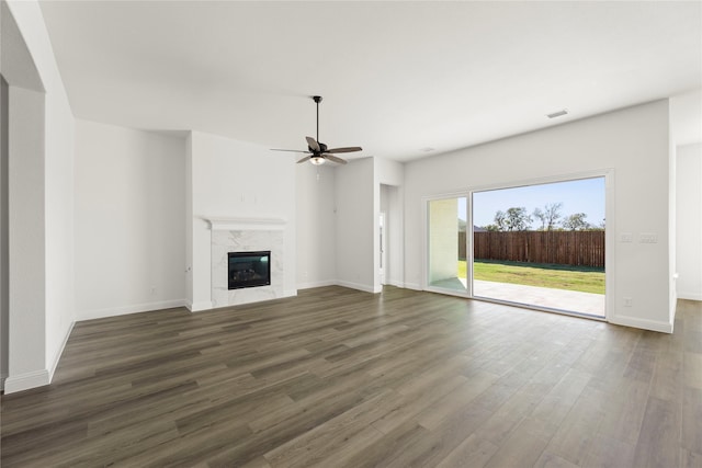 unfurnished living room with a high end fireplace, dark hardwood / wood-style floors, and ceiling fan