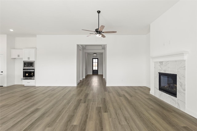 unfurnished living room featuring ceiling fan, a fireplace, and dark wood-type flooring