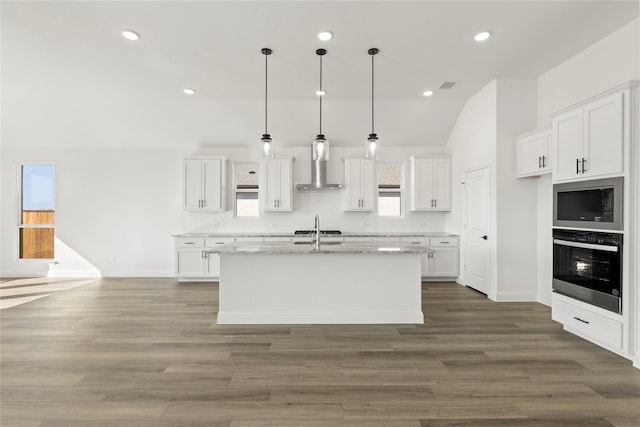 kitchen with white cabinetry, stainless steel oven, hanging light fixtures, tasteful backsplash, and an island with sink