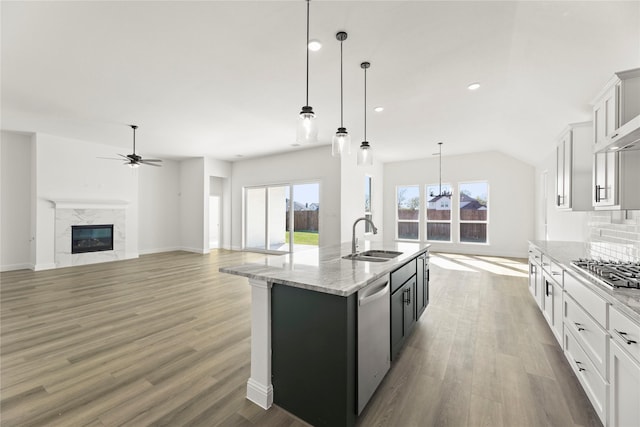 kitchen featuring appliances with stainless steel finishes, a kitchen island with sink, sink, white cabinets, and hanging light fixtures