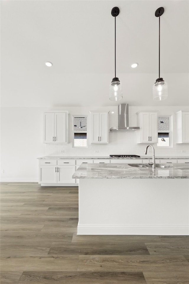 kitchen with white cabinets, light stone counters, and wall chimney exhaust hood