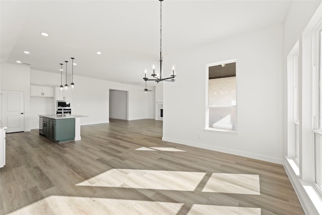 unfurnished living room with a healthy amount of sunlight, light wood-type flooring, sink, and a chandelier